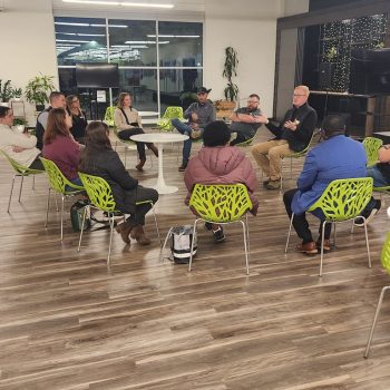 networking event members sitting in a circle - men and women of varying races.
