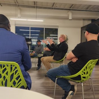 networking event members sitting in a circle - men and women of varying races.