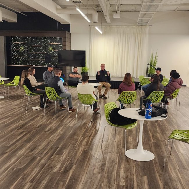 networking event members sitting in a circle - men and women of varying races.