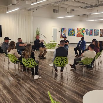networking event members sitting in a circle - men and women of varying races.