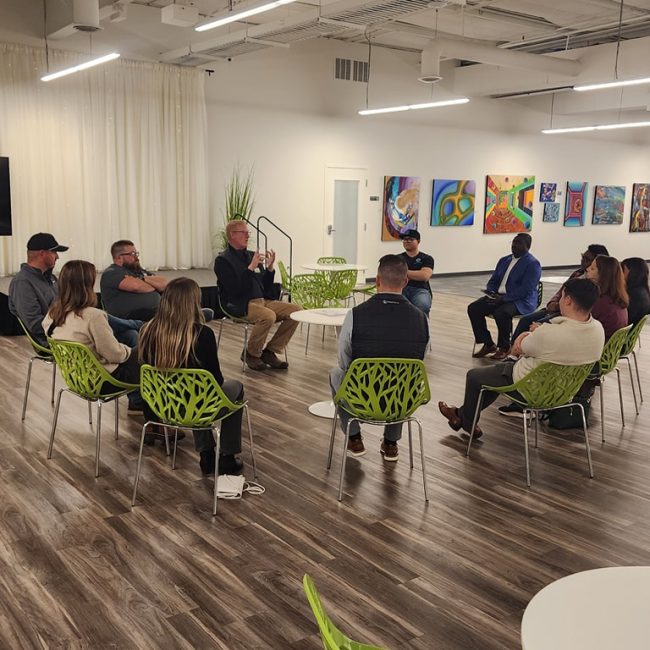 networking event members sitting in a circle - men and women of varying races.