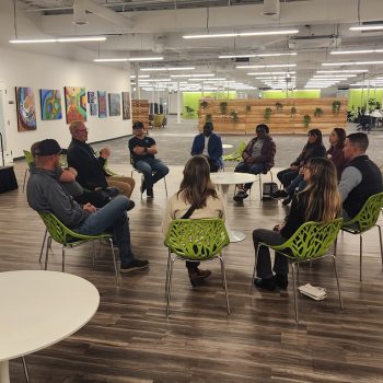 networking event members sitting in a circle - men and women of varying races.